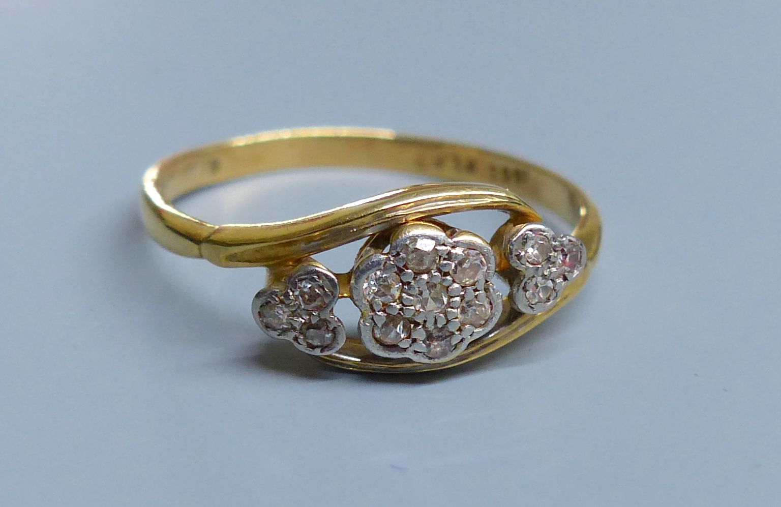 A 1940s? 18ct, plat and diamond set heart and flower head shaped triple cluster crossover ring, size P, gross 2.7 grams,
